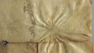 <a href='http://www.ra.ee/pargamendid/index.php/et/parchment/view?id=15967&_xr=eNpLtDK0qs60MrBOtDKBMIqtDM2slAoSi5IzclPzSvSLU0FMJaC4uZVSUWpacn5KKohnCOSG%252BDjqGRkb6BnqOTnFm5voZ4IlrJQKobQhiLawUspJzEsvTUwH6zOyUkotUbKurQUA0KQjzQ%253D%253D' target='_blank' rel="noopener noreferrer">Ürik TLA.230.1.BB_74/i</a>, 1568. a. </ br>
Kokkutõmbumine.
Pärgamendi lokaalse degradeerumisega kaasnev materjali kokkutõmbumine ja sellega kaasnev deformatsioon.